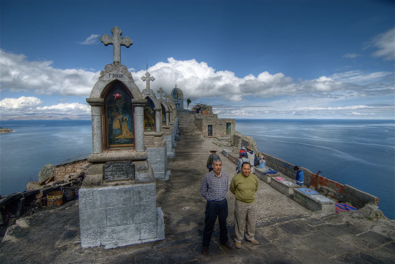 Local men standing on the hill overlooking the town of Copacabana on the shores of Lake Titicaca in Bolivia. The hilltop was a shrine where the locals came to light candles, make offerings, and buy small amulets. October 2007.