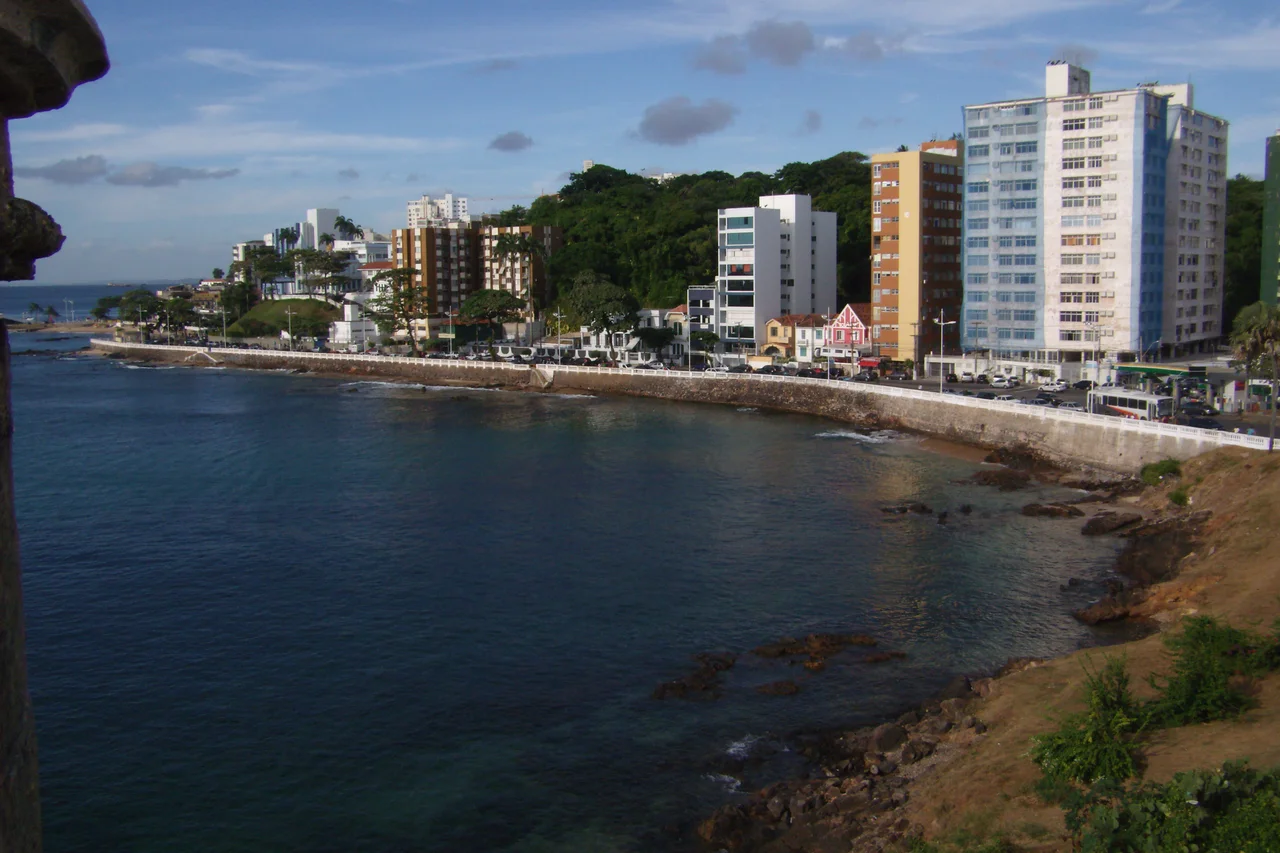PT: A praia do Porto da Barra está situada no bairro da Barra, banhada pela Baía de Todos os Santos.
Localiza-se no bairro da Barra; limita-se ao sul pela encosta que é formada pela Ladeira da Barra, passando pelo Hospital Espanhol indo até o Farol da Barra, passando pela fortaleza de Santa Maria. (Fonte: Wikipédia)

EN: Porto da Barra Beach is located in the city of Salvador, Bahia. It is located at the entrance of the Bahia de Todos os Santos, with a small, white colonial fort at one end and a whitewashed church sitting up on a hill at the other. As the beach is in a bay, the water is calm (given that it is right in the heart of Brazil's third-largest city) . And in a country with over 7,000 km of east-facing coastline, the Porto is one of the few facing west, and sunsets can be seen from there.  (By: Wikipedia)