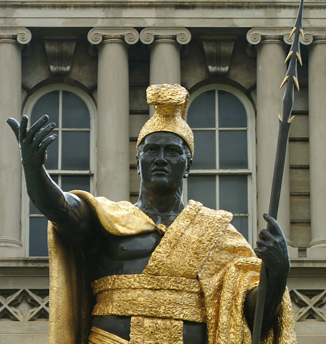 Statue of King Kamehameha I, standing in front of Ali'iolani Hale in Honolulu. Cast: 1881, bronze with gold leaf. Approx 8½ feet tall on a 10 foot concrete base. The pedestal has four bronze and gold leaf plaques with scenes from Kamehameha's life. Sculptor: Thomas Ridgeway Gould (1818–1881).