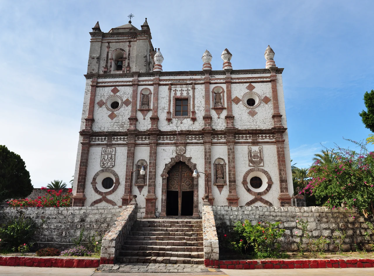 Baroque stone facade of Misión San Ignacio Kadakaamán — a 1786 Spanish mission in Baja California, central Baja California Peninsula, México.
Located in San Ignacio, an oasis village in Mulegé Municipality, northern Baja California Sur state.
In December 2009. Photo by Gregg M. Erickson.