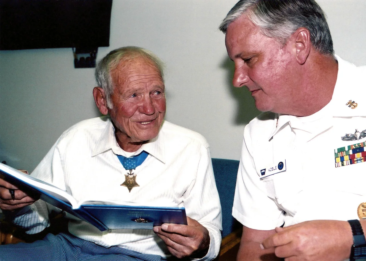 U.S. Navy retired Lieutenant John W. Finn (left) is the sole surviving Medal of Honor recipient from Pearl Harbor and the oldest living Medal of Honor recipient. U.S. Navy Master Chief Quartermaster (QMCM) Kobel (right), Command Master Chief of the Naval Leadership Training Unit (NLTU), speaks with John W. Finn about an entry in the Chief’s charge book. Location: U.S. Naval Amphibious Base, Coronado, California.