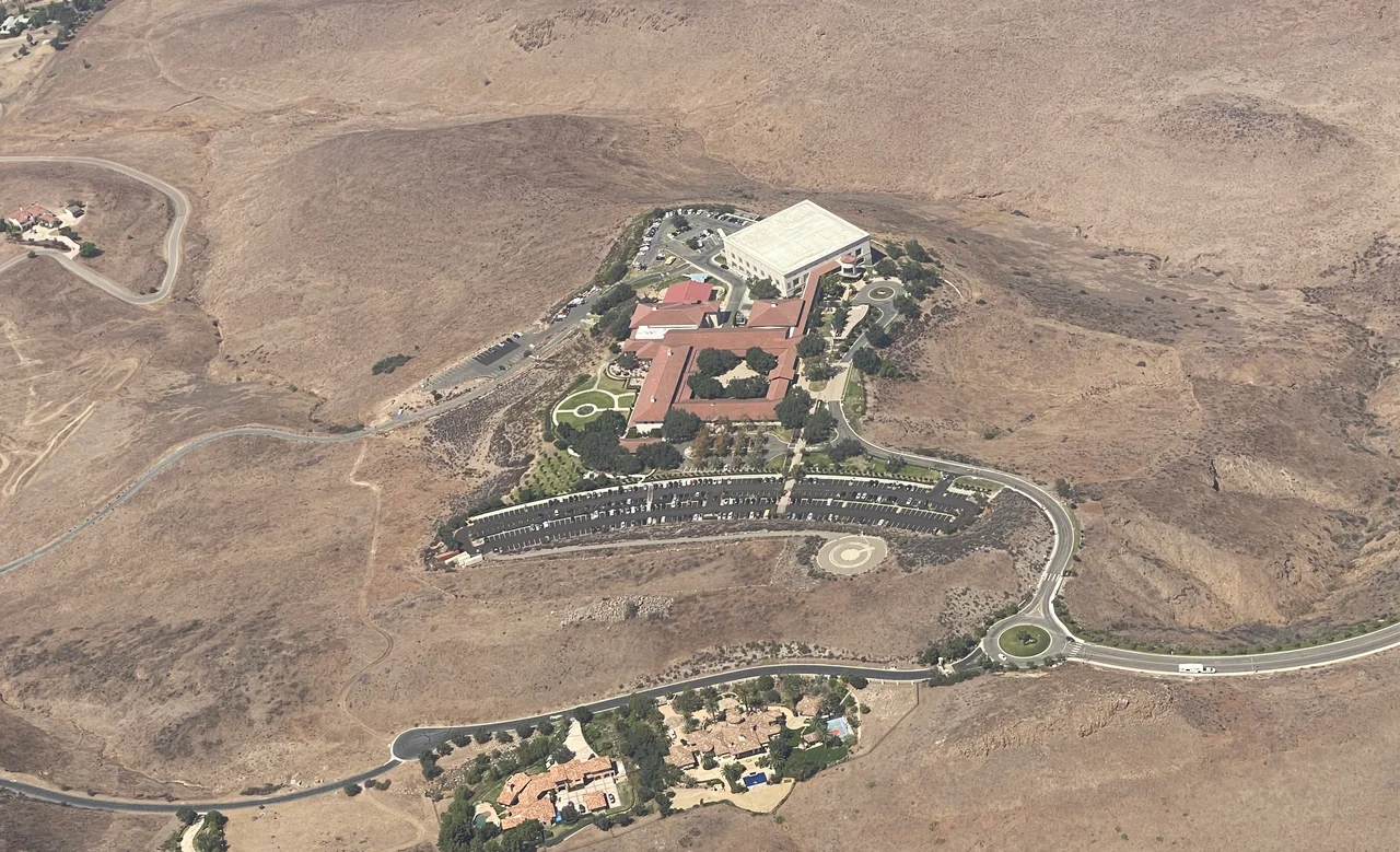 An aerial view of The Ronald Reagan Presidential Library in Simi Valley, CA as observed in 2021 - with Presidential Drive leading up to the site. Library building, Air Force One Pavilion, parking lots, and grounds can be seen. The library's F-14 Tomcat as well as the newly acquired F-117 Nighthawk Stealth Fighter can be seen in this photograph.