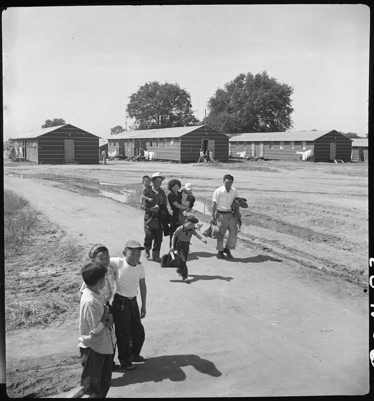 Scope and content: The full caption for this photograph reads: Sacramento, California. Another family of Japanese ancestry has just arrived at this Center by bus. Their baggage has been inspected for contraband and they have been registered, medically examined and are now being escorted by a volunteer guide to their assigned location in the barracks.