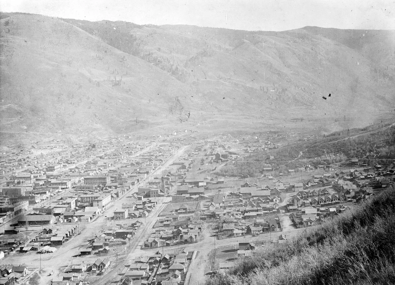 View of Aspen (Pitkin County), Colorado, is probably taken from Shadow Mountain (partially visible in foreground), looking at Smuggler Mountain. Aspen Mountain is to the right.