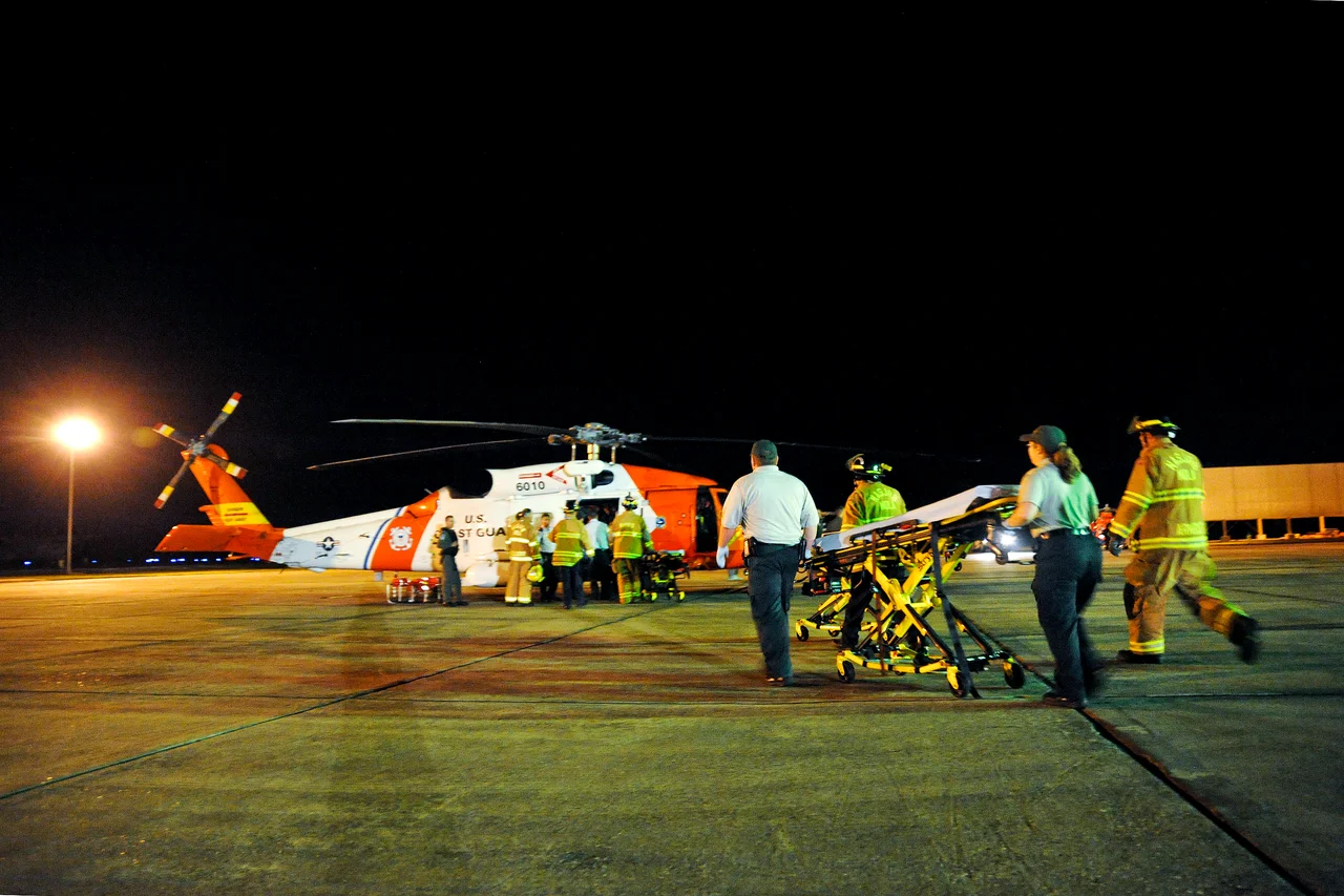 Emergency medical technicians rush a gurney to an awaiting HH-60 rescue helicopter and crew from Coast Guard Aviation Training Center Mobile, Alabama, on Coast Guard Air Station New Orleans. The helicopter crew medevaced multiple survivors from the mobile offshore drilling unit Deepwater Horizon after an explosion and fire caused the crew of the vessel to evacuate.