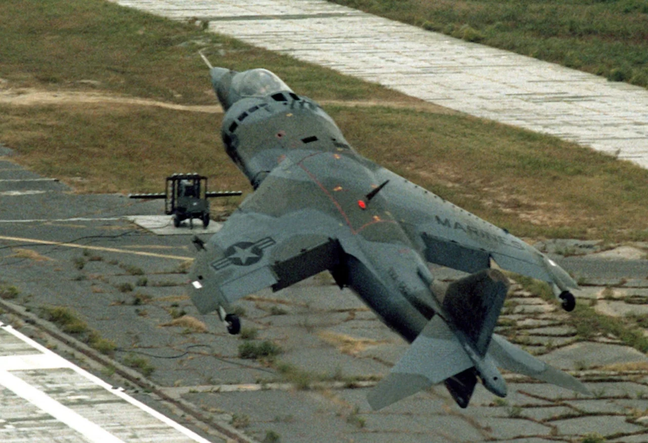 A U.S. Marine Corps Hawker Siddeley AV-8A Harrier from Marine Attack Squadron VMA-231 Ace of Spades taking off from the Marine Corps Auxiliary Landing Field Bogue, North Carolina (USA). Note the optical landing mirror used on aircraft carriers in the background.