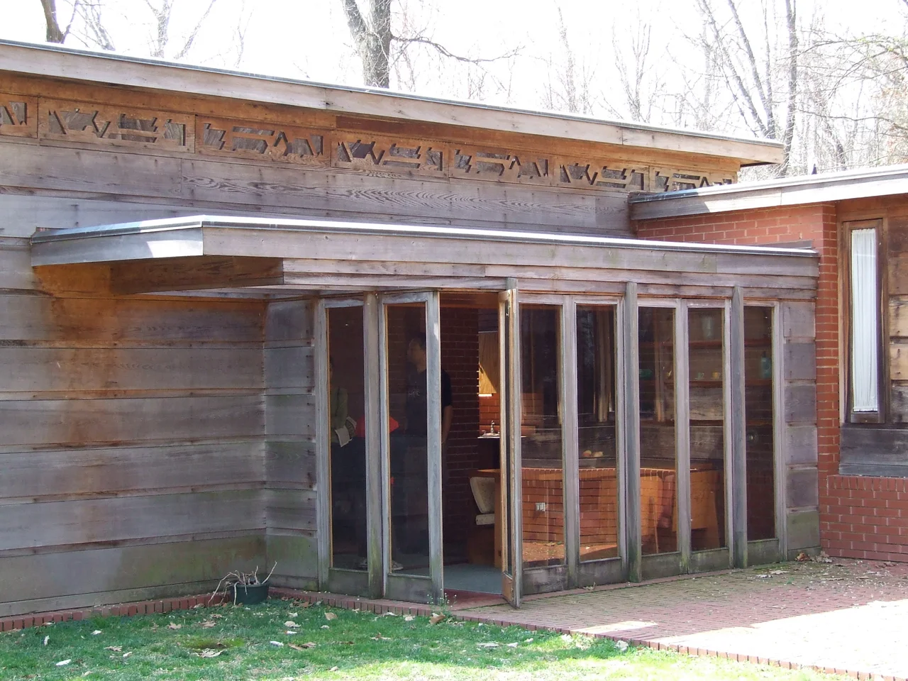 Exterior of Pope-Leighey House, with dining room visible through full-length windows.