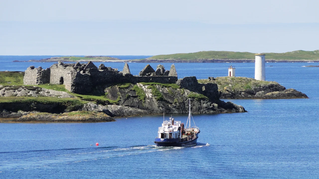 Inishbofin harbour, Port Island with Cromwell's Barracks and the light on Gun Rock, a ship leaving the harbour