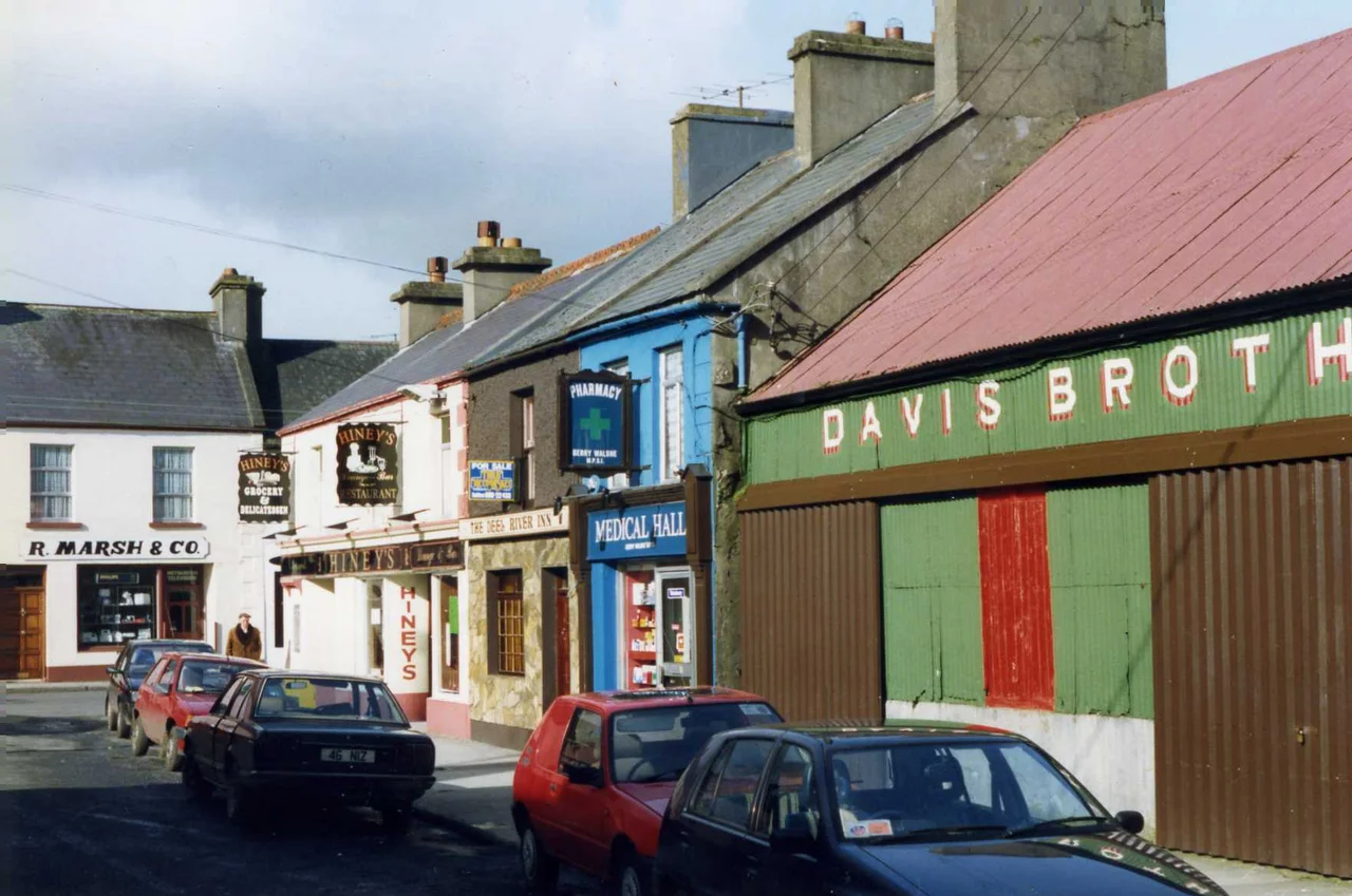 Crossmolina, featuring R.Marsh &amp; Co.  Hiney's Grocery Delicatessen and Restaurant, THe Deep River Inn, the Derry Walshe's Medical Hall and the nicely signwritten corrugated iron of Davis Brothers.
