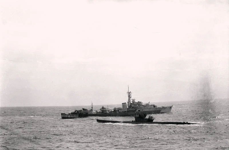 The German submarine U-516, with a black surrender flag flying, awaiting instructions from the Royal Navy destroyer HMS Cavendish (R15), 10 May 1945.