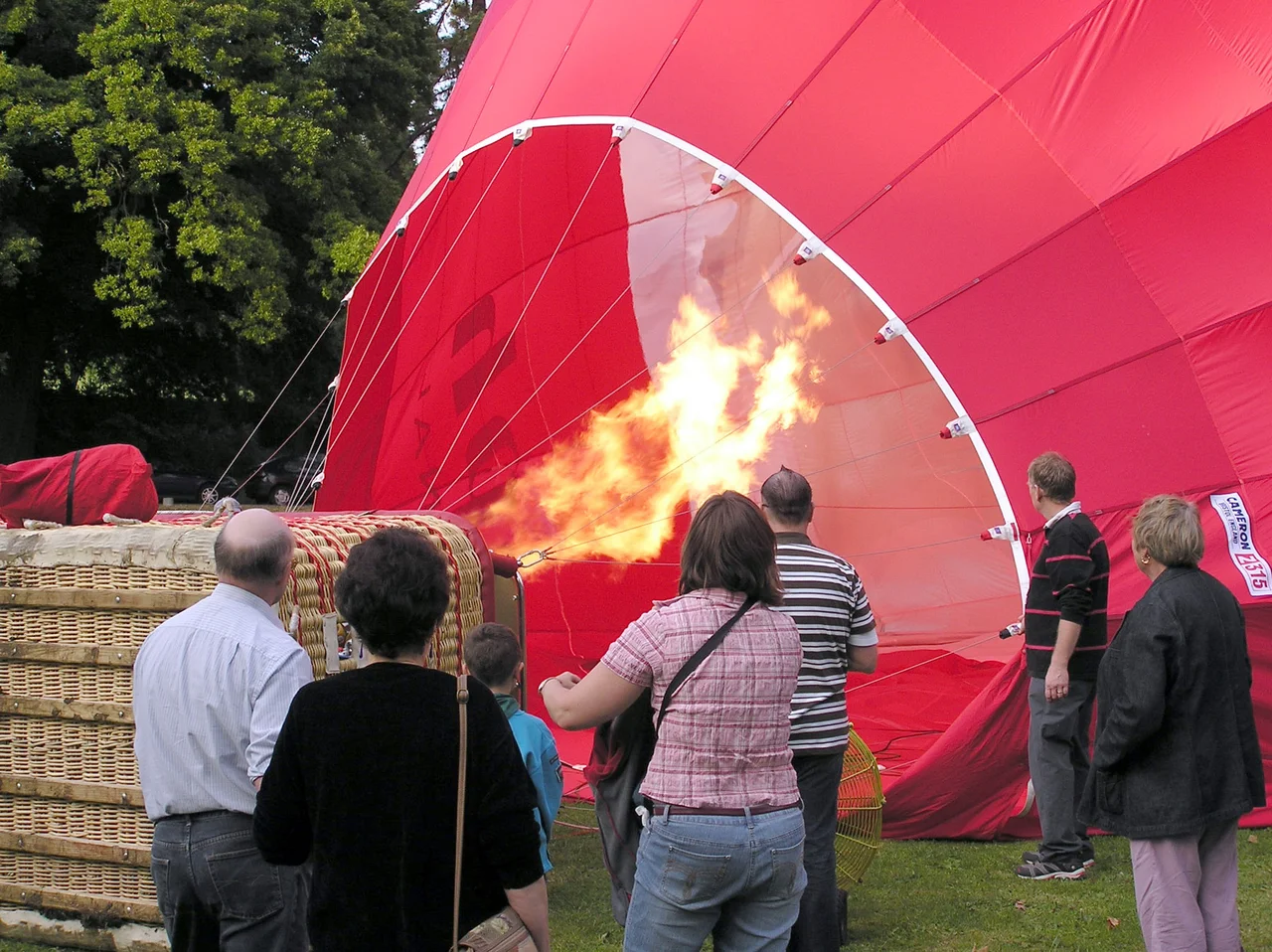 Firing the propane burners during final inflation of a hot air balloon, Royal Victoria Park, Bath, England.
This balloon carries 16 passengers and the pilot.
Photographed by Adrian Pingstone on 21st September 2005 and placed in the public domain.