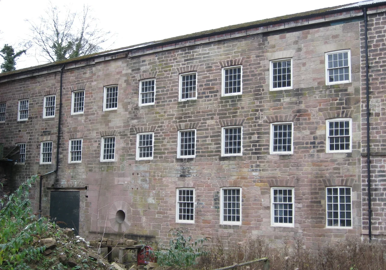 Arkwright's original mill, Cromford--view from mill yard, showing raised supply structure, reconstructed bearing opening, rebuilt first three floors of original five