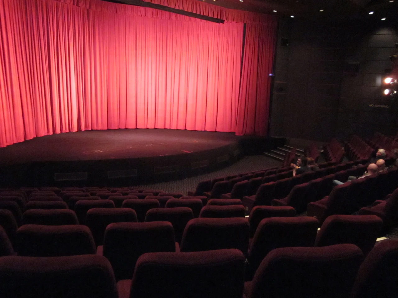 Interior of the Pictureville Cinema, Bradford, part of the National Media Museum.  The curtains cover a curved screen ready to show a Cinerama film.  A flat screen can be lowered from the top (just visible below the pelmet) for other films.