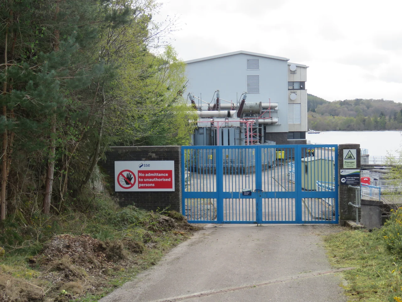 The north gate to the Foyers 300MW power station, showing part of the main building and the transformer station. An underground cable connects this to the 275kV switching station some 3000 feet (910 m)  to the north.