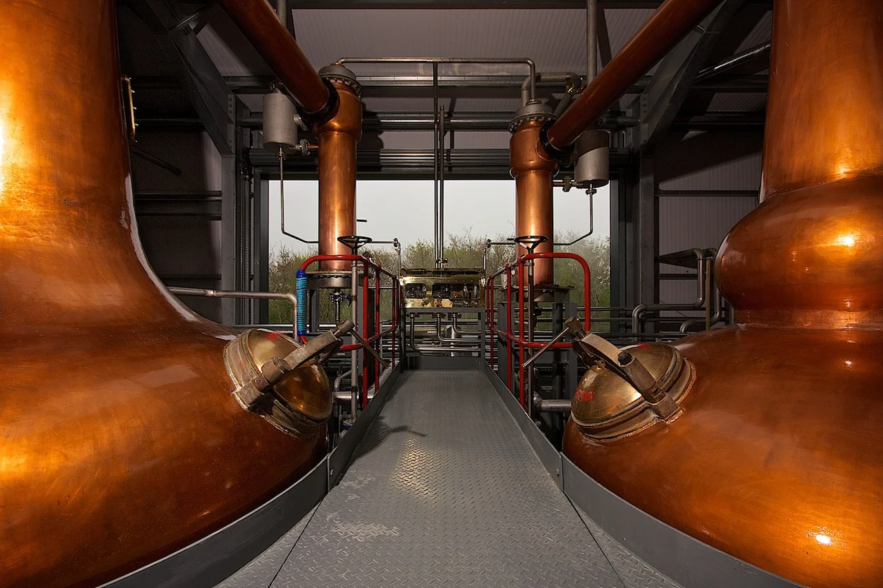 Image of Wolfburn Distillery's wash still (on left) and spirit still (on right), with the spirit safe in the background.
