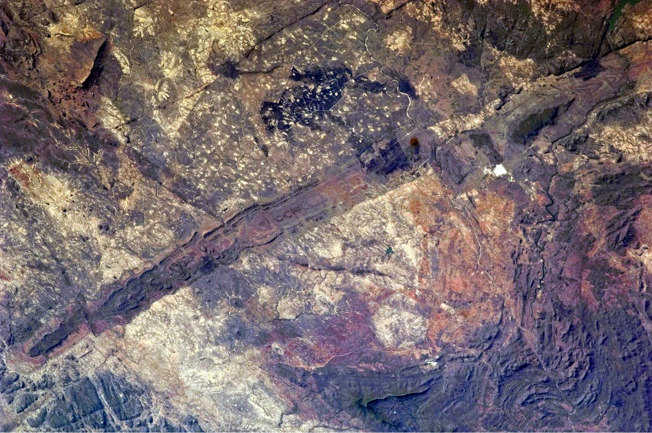The Great Dyke of Zimbabwe. Although originally named as a dyke (The Great Dyke of Rhodesia) when first studied by geologists in the 19th century, it is now known to be a layered lopolith, not a dyke. The southern end of the dyke is captured in this  photograph taken by astronauts. Two large burn scars from fires are visible at image top centre. North is to the right.