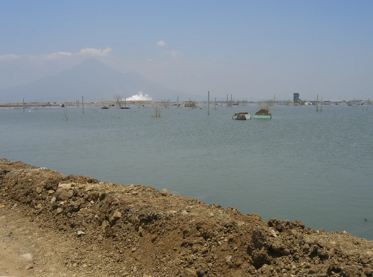 Lake created by mud with steaming mud flow in background, the remnants of Sidoarjo's sub town.
