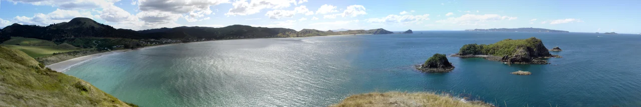 Panorama of Opito Bay on the Coromandel Peninsula, New Zealand. Rabbit Island in the foreground on the right, with Great Mercury Island visible on the horizon