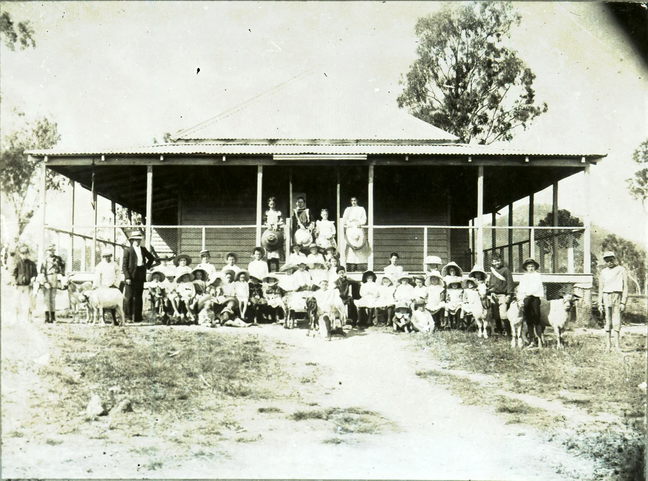 Group of children, adults and goats outside a building, thought to be Maytown School, circa 1900
