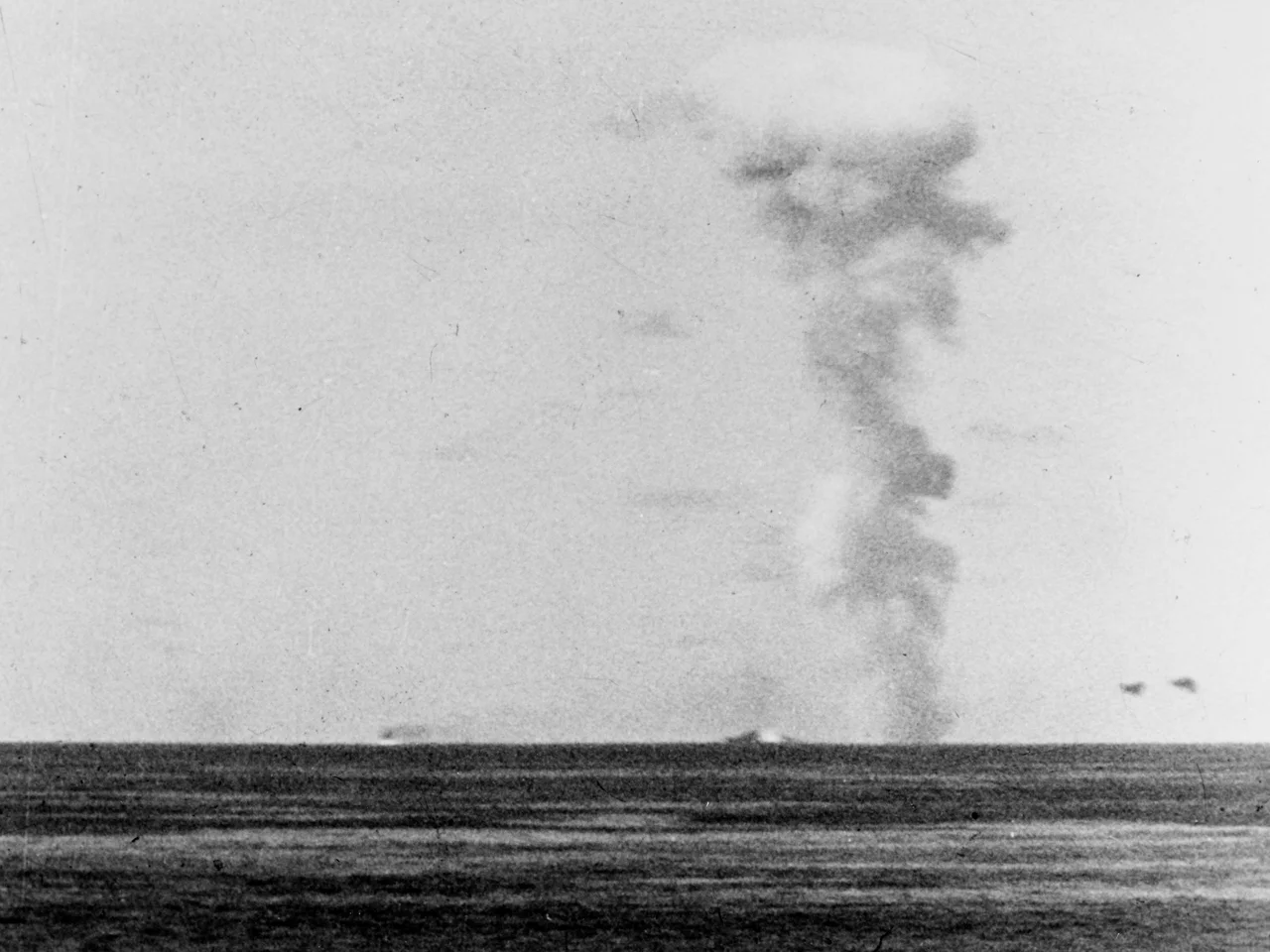 The U.S. Navy destroyer USS Brownson (DD-518) exploding off Cape Gloucester, New Britain, on 26 December 1943. At approximately 14:42 hrs, Brownson was hit by two bombs from a Japanese dive bomber while screening the landings on Cape Gloucester. The bombs struck to starboard of the centerline, near the number two stack. A tremendous explosion followed, and the entire structure above the main deck as well as the deck plating, was gone. The ship listed 10 to 15 degrees to starboard, and settled rapidly amidships with the bow and stern canted upward. Brownson suffered the loss of 108 of her crew.