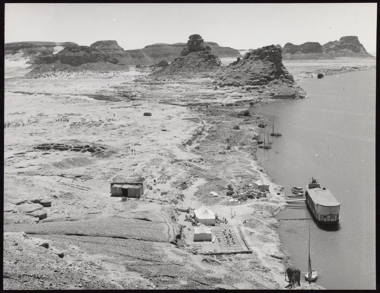 Aerial view of the site of the American Research Centre's archaeological expedition at Gebel Adda. The dark cavities to the left are the excavations of an early Christian cemetery. An ancient course of the Nile ran through the cliffs in the background.