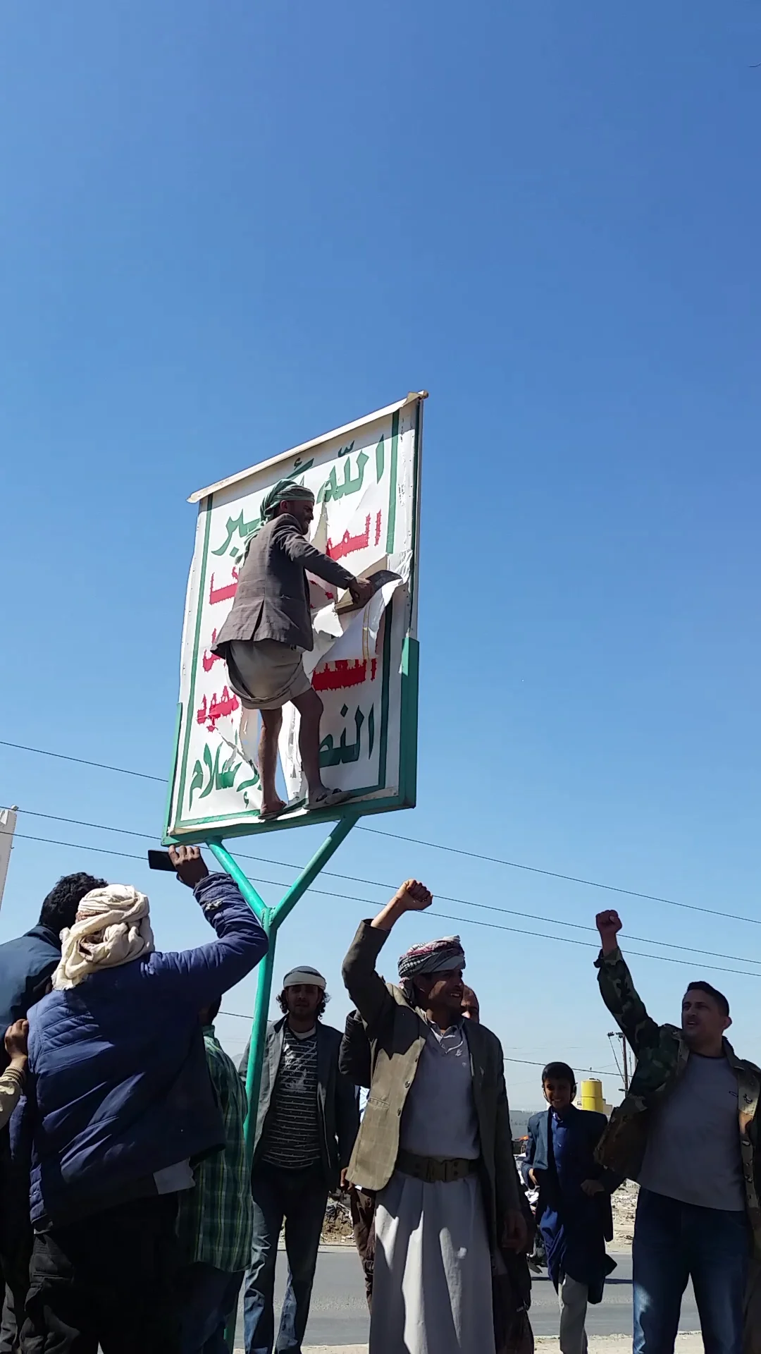 Protestors tear down a Houthi poster amid the battle for the city between pro-Houthi forces, and forces loyal to ex-President Ali Abdullah Saleh.