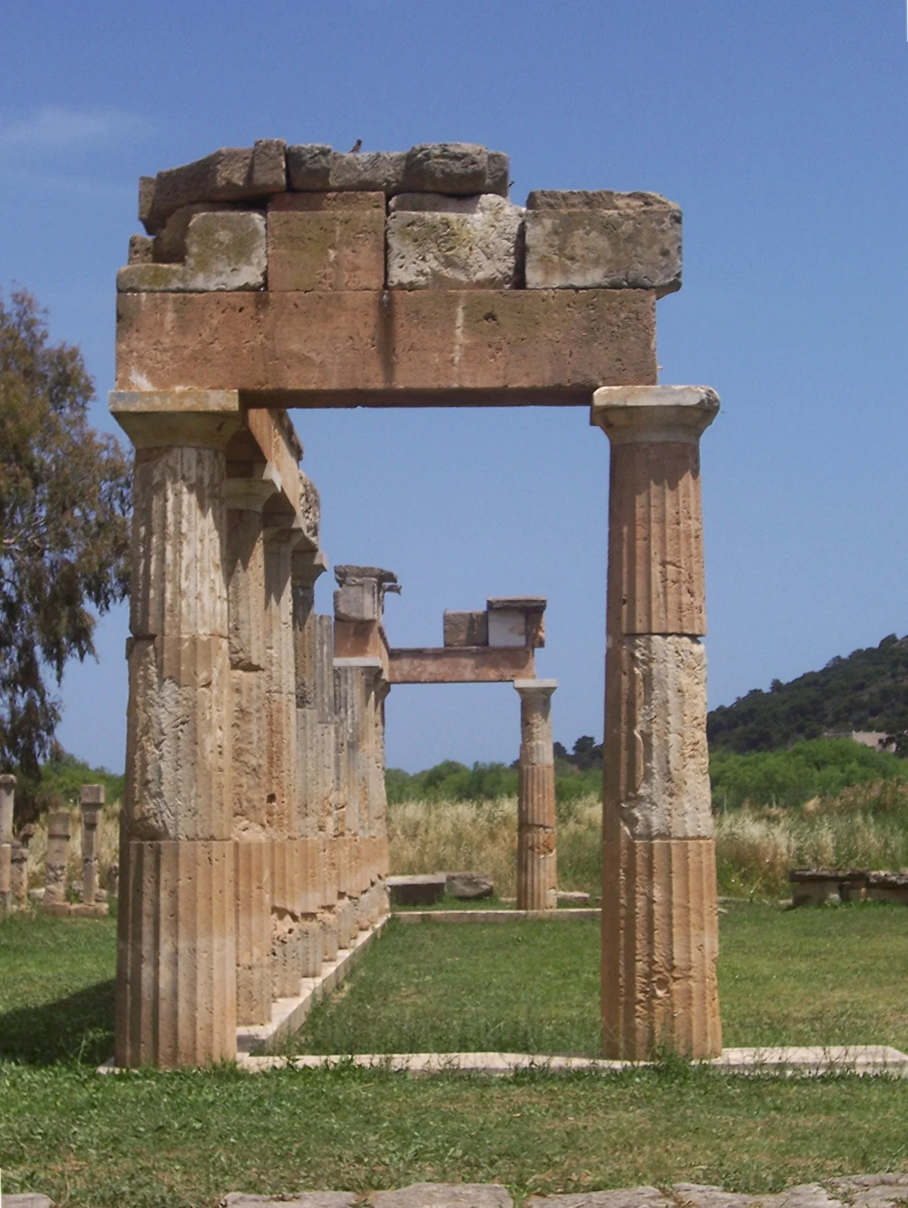 The first known temple at the sanctuary - dating to the late 6th century BCE - rests on a low rock spur south of the river and is aligned toward the east on a foundation measuring c. 11 by 20 m. Little is preserved beyond partial lower courses and cuttings in the bedrock for the same. There are a few remains of the architecture that allow a certain identification of the temple as being of the Doric order. The Persians destroyed the sanctuary structures in 480 BCE and took the cult statue back to Susa. The temple was reconstructed in the 420s BCE. Although the temple is poorly preserved, it can be reconstructed to have had four columns in the cella and an adyton at the rear of the cella. The presence of an adyton is asserted for the temple of Artemis at Loutsa (Artemida) 6.1 km to the north and the temple of Artemis at Aulis 67 km northwest. This feature may also be shared by the 6th century BCE Temple of Aphaea on Aigina. Schwandner links the shared feature of an adyton with a common, regional practice in the cult of Artemis. There is disagreement on the question of the temple having been hexastyle-prostyle (6 columns across the front only) or distyle in antis (2 columns between projecting walls) in plan. There is a stepped retaining wall on the northern side of the temple platform, which may be the steps mentioned by Euripides.
