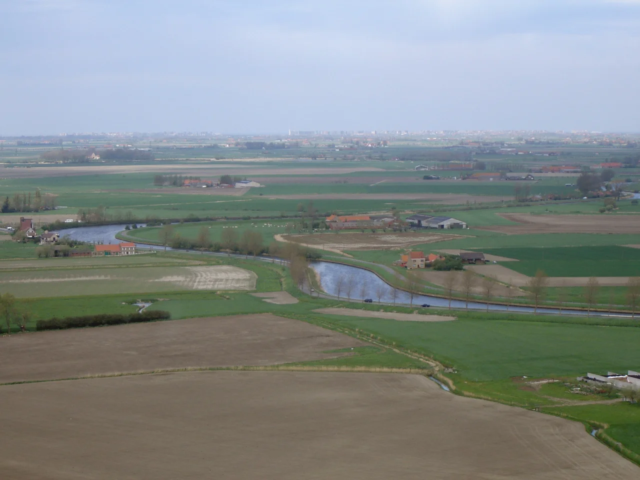 View on the West Flemish polders, seen from the IJzertoren tower in Diksmuide. In the middle the river IJzer (Yser). On the horizon the high-rise buildings along the Belgian coastline.