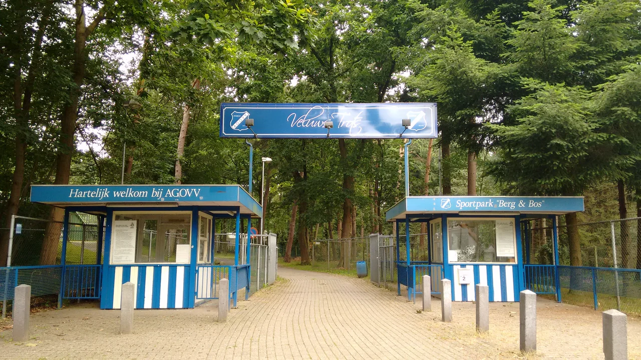 De entree van Sportpark Berg & Bos van voetbalclub AGOVV (Apeldoorn). Teksten: 'Hartelijk welkom bij AGOVV', 'Veluws Trots', 'Sportpark "Berg & Bos"'.