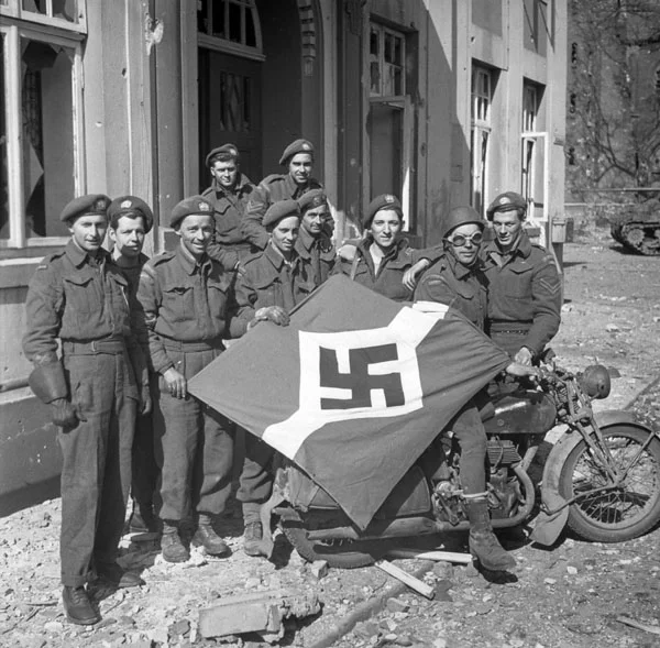 Personnel of The Lake Superior Regiment (Motor) with a Hitler Youth flag at Friesoythe, Germany on 16 April 1945.