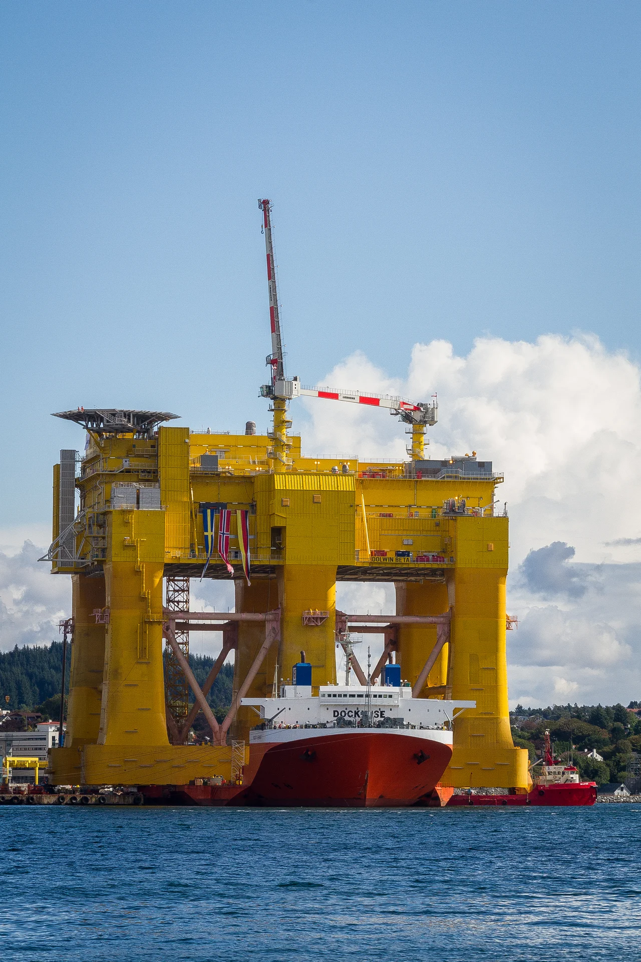 Mighty Servant 1 heavy-lift ship transporting DolWin beta offshore HVDC converter platform at Haugesund, Norway.
Not that it is such a great shot in its own right, but I just had to take a picture of this! It is right outside my doorstep. Viewed from my house on the Karmøy island towards east and the city of Haugesund.
No - I am not playing with perspective or anything here. That ship (Mighty Servant 1) IS actually carrying this huge structure. The project is a cooperation between Aibel Norway and ABB. The structure itself has been built in Dubai, and is now at the Aibel yard in Haugesund for final equipment installations and testing. It has a capacity of 900 MW and will receive power from 240 wind turbines in the North Sea from Q2 2015.