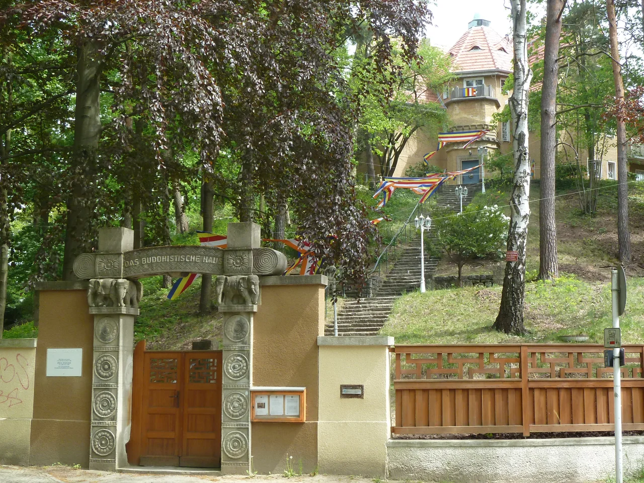 The Elephant Gate leads to Das Buddhistische Haus, Berlin Frohnau; Vesak festival flags are present