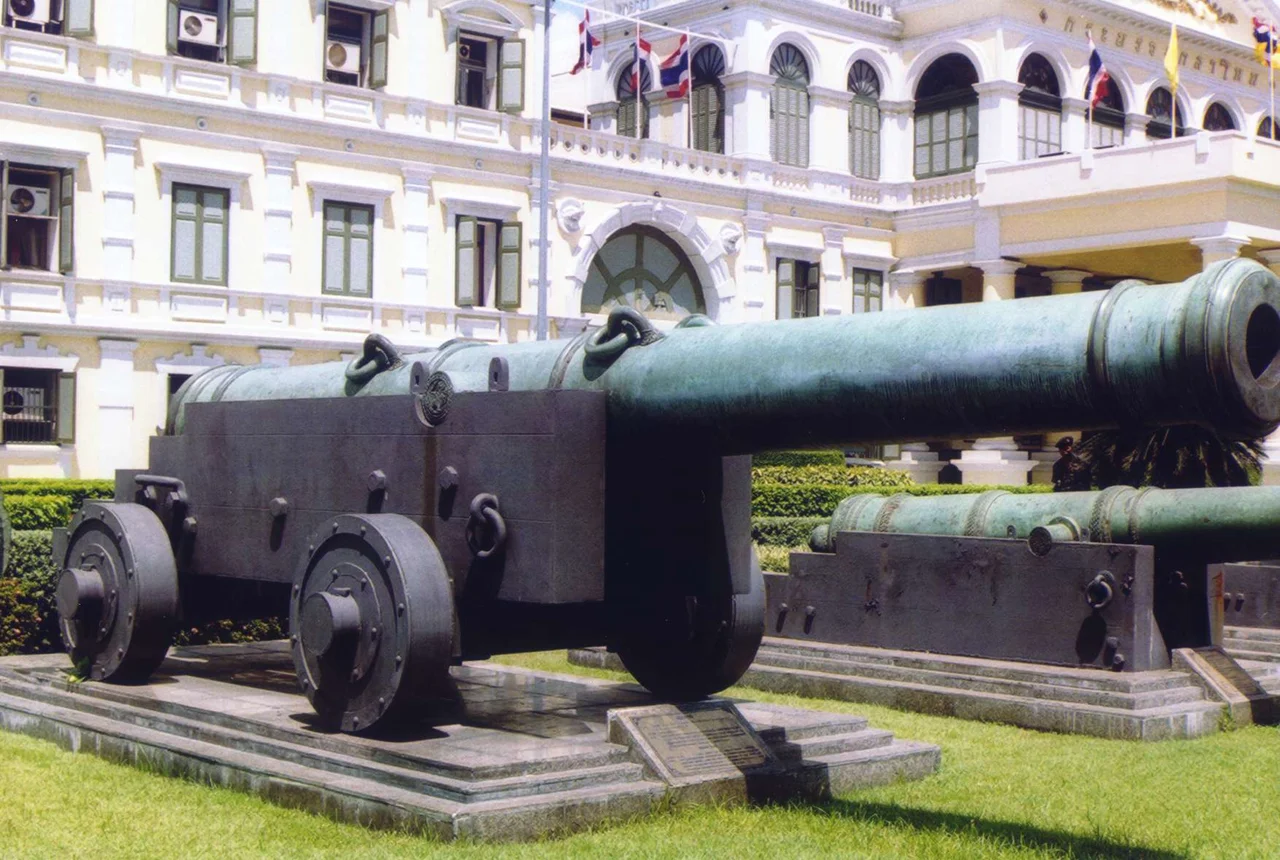 One of the cannons in front of the Ministry of Defence, Bangkok, Thailand. Photo taken before the re-alignment of the canons in 2004, so it points toward Wat Phra Kaew, not to the south like it does now.
The canon depicted may be Phraya Tani (พญาตานี), or the cannon cast to be a replica of it. (can anyone identify it).
Photo taken by User:Ahoerstemeier in 2003.