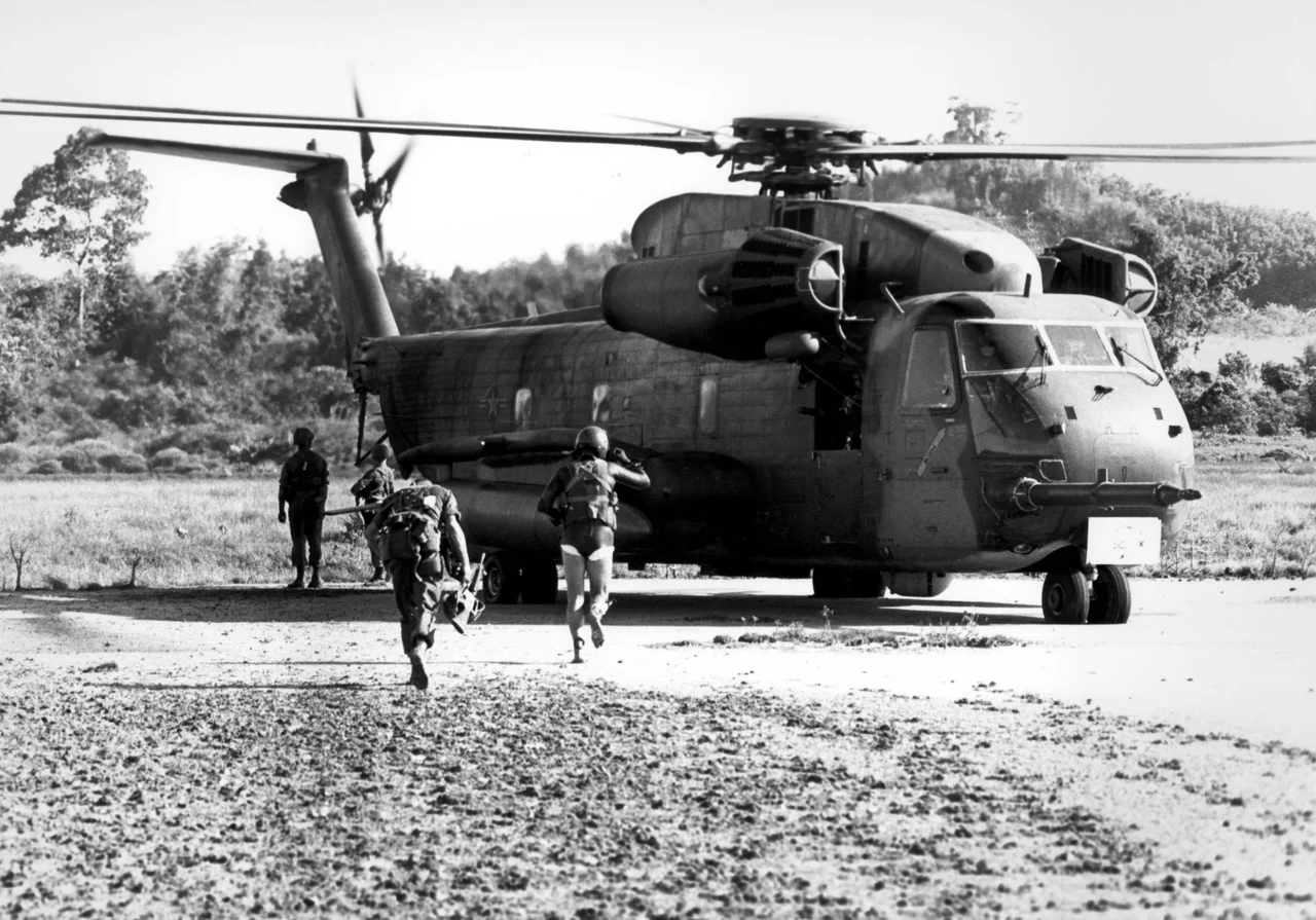 A Marine and Air Force pararescueman Stu Stanaland of the 40th Aerospace Rescue and Recovery Squadron (in wet suit) run for a U.S. Air Force Sikorsky HH-53C Jolly Green Giant helicopter during the assualt on Koh Tang Island to rescue the U.S. Merchant ship Mayaguez and its crew, 15 May 1975.