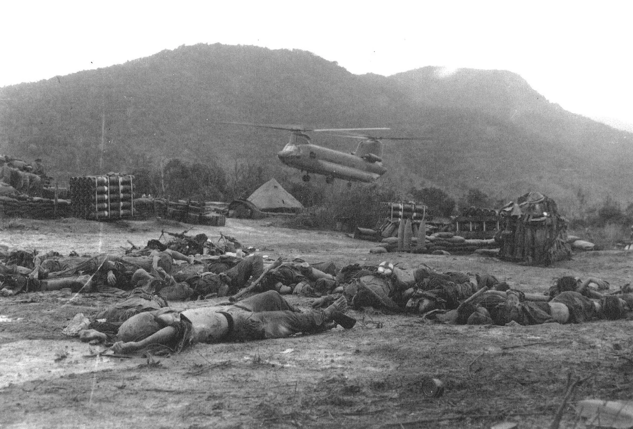 Dead North Vietnamese soldiers on LZ Bird, Chinook rising above the field, Vietnam