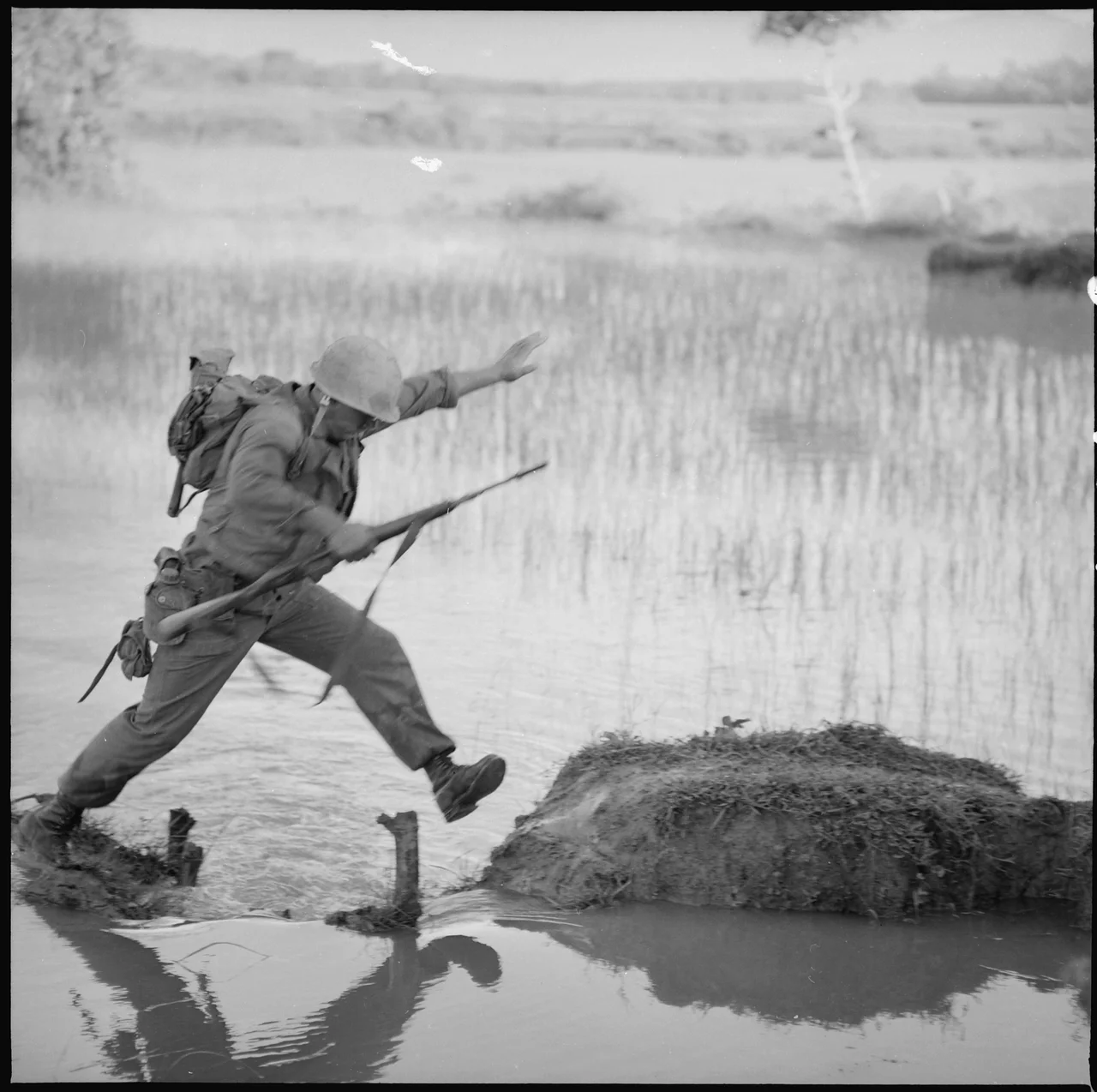 Vietnam....A Marine rifleman with Company H, 2nd Battalion, 5th Marines, Leaps across a break in a rice paddy dike... - NARA - 532474.tif